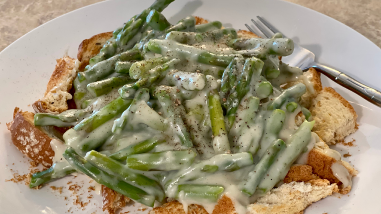 white place filled with creamed asparagus over toast