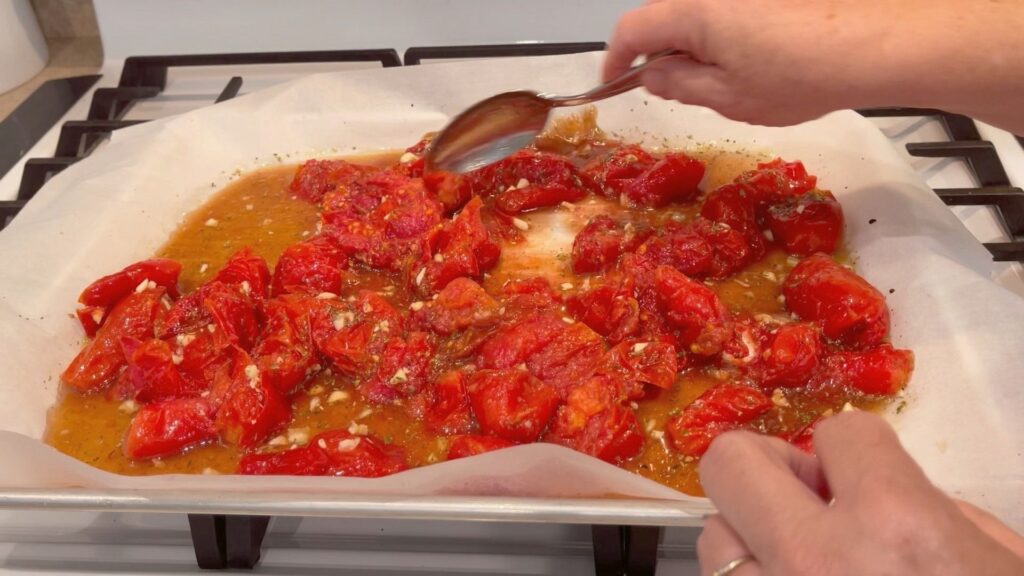 stirring up the tomato mixture on the baking sheet halfway through the baking process