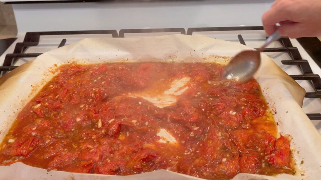 final stir of the roasted tomato showing that the water has evaporated and they are ready to be removed from the oven